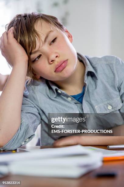 10 years old blonde school boy while doing homework. - 10 11 years boy stock-fotos und bilder