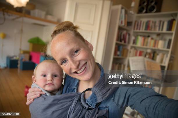 selfie of happy mother holding baby in sling at home - blonde woman selfie stock pictures, royalty-free photos & images