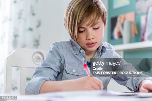 10 years old blonde school boy while doing homework. - 10 11 years boy stockfoto's en -beelden