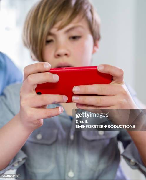 10 years old blonde school boy gaming with smart phone. - 10 11 years old stock pictures, royalty-free photos & images