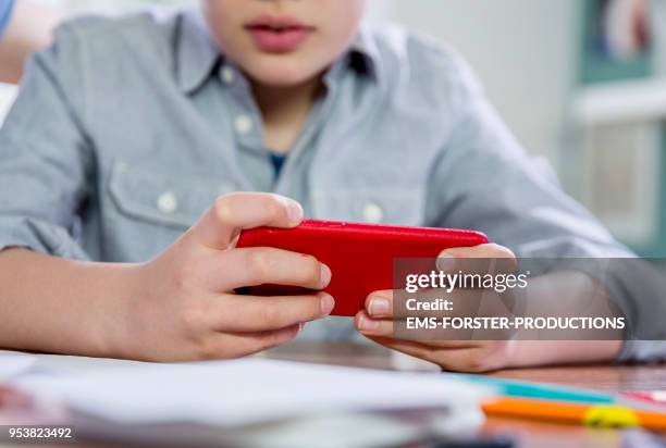 10 years old blonde school boy gaming with smart phone. - child smartphone stock pictures, royalty-free photos & images