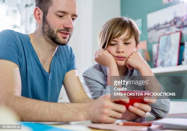 private tutoring lesson for 10 years old blonde elementary school boy while doing his homework together with male tutor in his thirties. - 35 39 years stockfoto's en -beelden