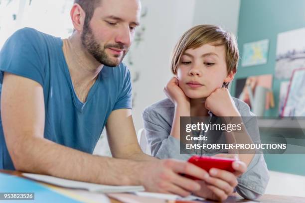 private tutoring lesson for 10 years old blonde elementary school boy while doing his homework together with male tutor in his thirties. - 10 to 13 years stock pictures, royalty-free photos & images