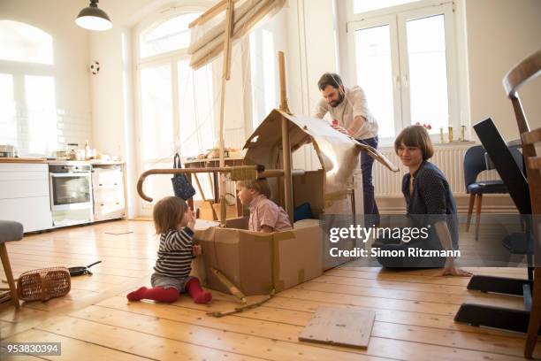 parents and two children playing with cardboard sailingboat at home - resourceful stock pictures, royalty-free photos & images