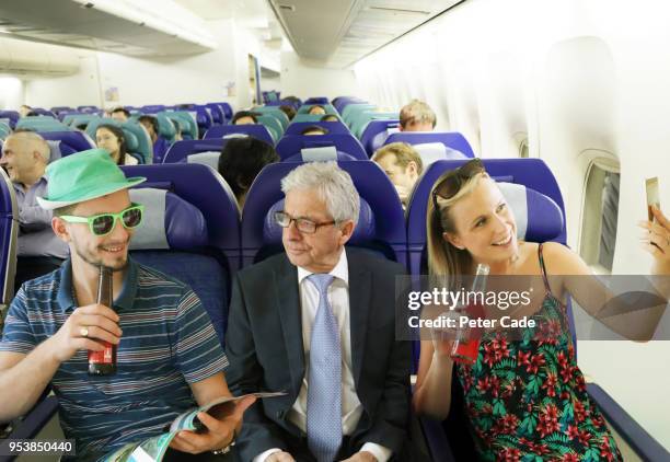 annoyed man on airplane between young adults - funkenflug stock-fotos und bilder