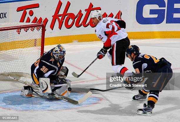 Ryan Miller of the Buffalo Sabres makes a save on Chris Kelly of the Ottawa Senators as Jason Pominville of the Sabres defends at HSBC Arena on...