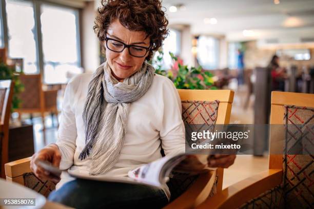 woman having lunch at a restaurant - reading magazine stock pictures, royalty-free photos & images