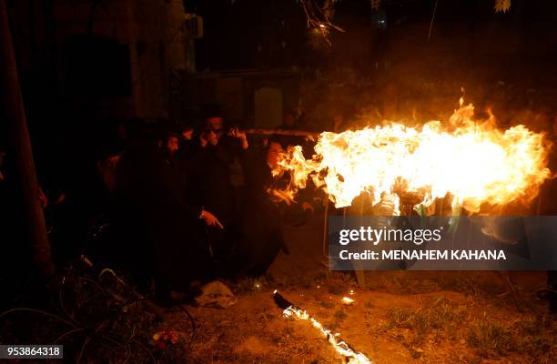 Ultra-Orthodox Jews hold a burning stick to light a bonfire in Jerusalem's ultra-Orthodox Mea Shearim neighbourhood on May 2 during celebrations for...