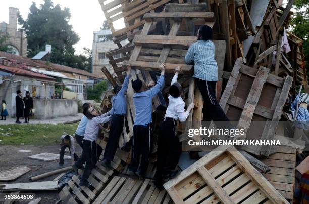 Ultra-Orthodox Jewish children climb up a bonfire to be lit in the evening in Jerusalem's ultra-Orthodox Mea Shearim neighbourhood on May 2 to...