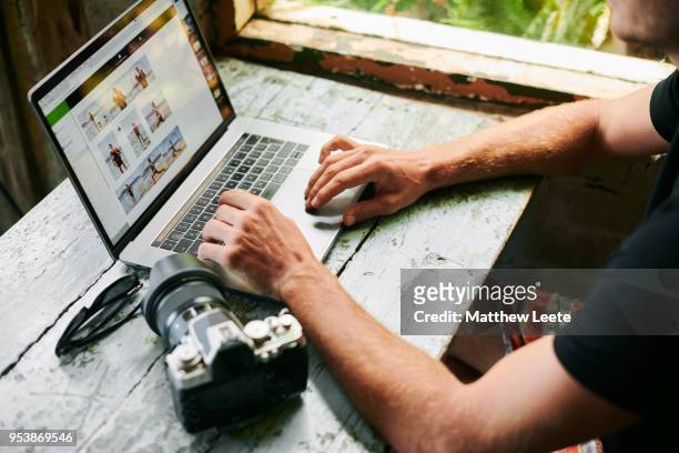 male on laptop in beach hut - how to upload fotos imagens e fotografias de stock