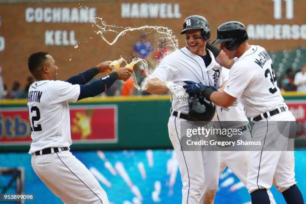 John Hicks of the Detroit Tigers celebrates his game winning RBI bunt in the 12th inning to beat the Tampa Bay Rays 3-2 with Leonys Martin and James...