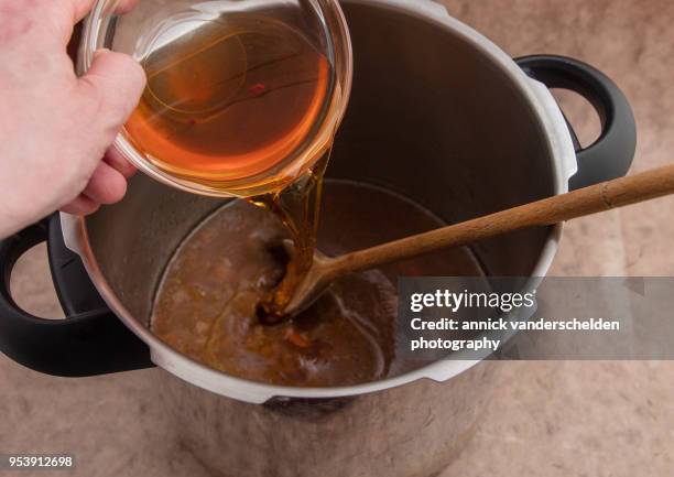 pouring apple cider vinegar in pressure cooked beef gravy. - sugo di carne foto e immagini stock