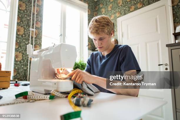 young man sewing textile at home - sewing stock pictures, royalty-free photos & images