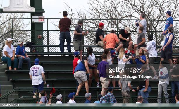 Fans in the bleachers watch a three-run home run ball hit by the Colorado Rockies' Nolan Arenado sail onto Waveland Avenue in the eighth inning...
