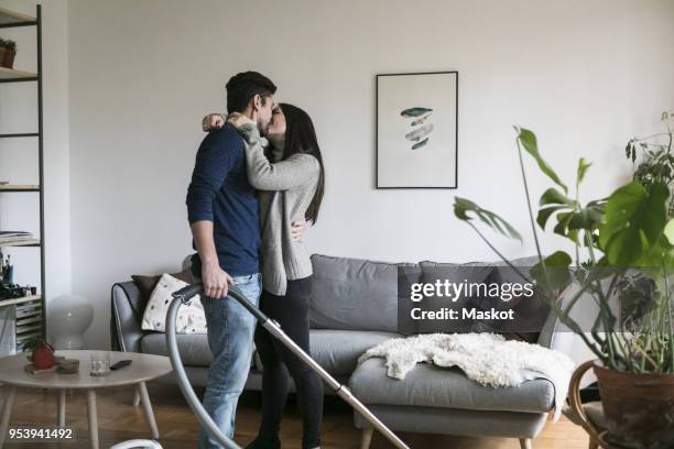 couple kissing while cleaning living room at home - woman cleaning for man stock pictures, royalty-free photos & images