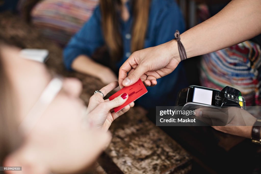 Close-up of female customer giving credit card to owner at restaurant