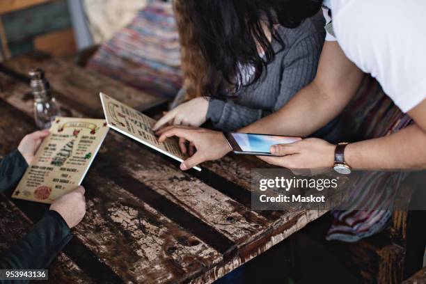 owner using digital tablet while explaining menu to customers at table - waiter tip stock pictures, royalty-free photos & images