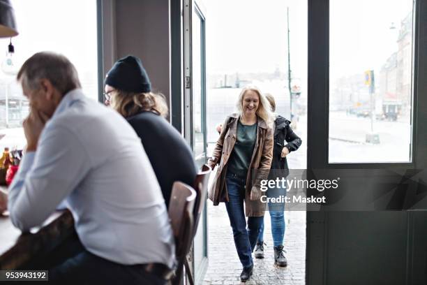 women entering from open door while men sitting at restaurant - returning customer stock pictures, royalty-free photos & images