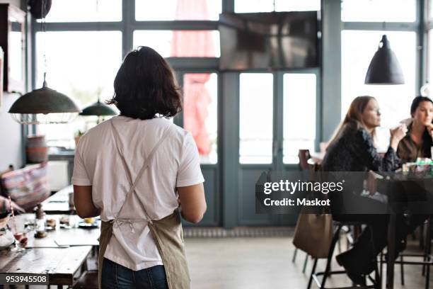 rear view of waiter walking by female customers at restaurant - schürze mann rückansicht stock-fotos und bilder