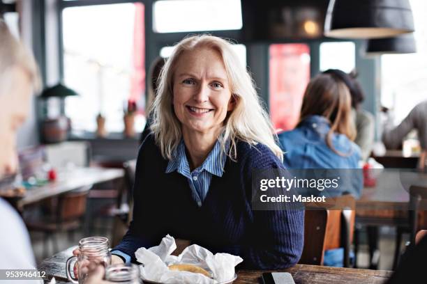 portrait of smiling mature woman sitting with man at dining table in restaurant - sitting at table looking at camera stock pictures, royalty-free photos & images