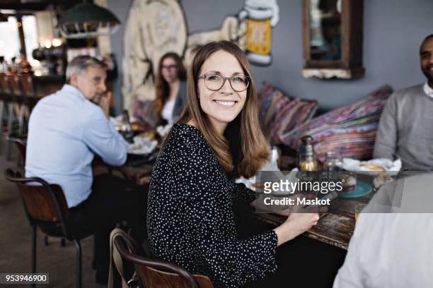 portrait of smiling woman holding mobile phone while sitting with friends at table - brunch stock-fotos und bilder
