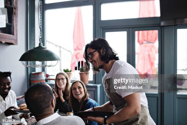 smiling waiter talking to happy customers at restaurant - kellner tablett stock-fotos und bilder