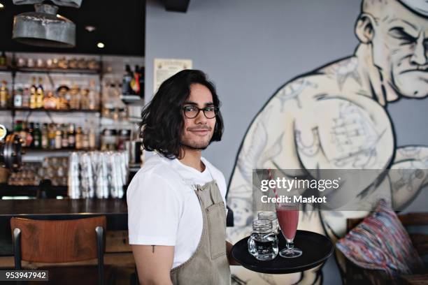 portrait of confident owner holding drink in serving tray at restaurant - kellner tablett stock-fotos und bilder