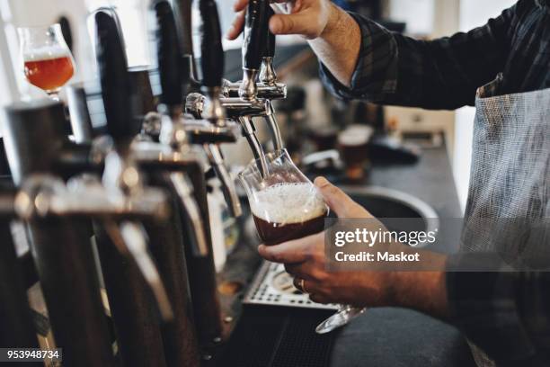 midsection of bartender filling glass while using beer tap at restaurant - craft beer imagens e fotografias de stock