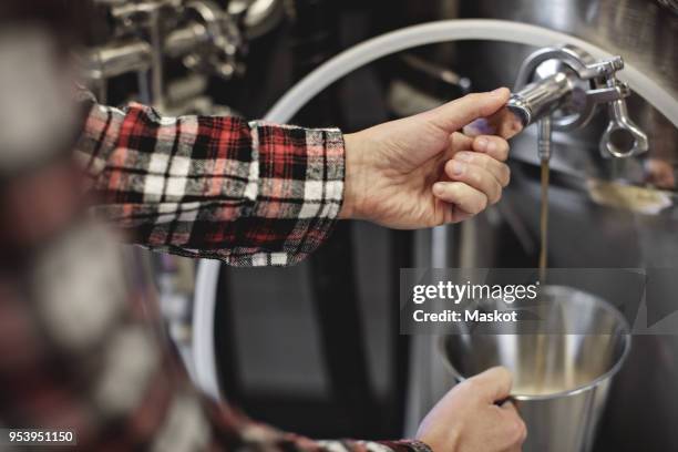 cropped image of female manager collecting beer from storage tank at brewery - bier brouwen stockfoto's en -beelden