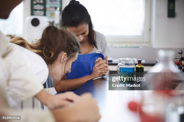female students looking at liquid solution in beaker in chemistry laboratory - liquid solution stock pictures, royalty-free photos & images