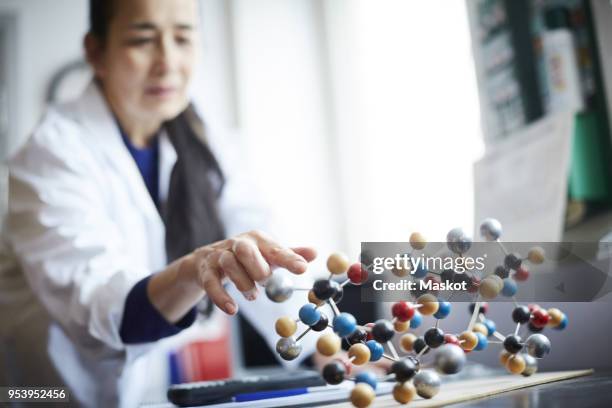 mature teacher touching molecular structure on table at university chemistry laboratory - scientist standing next to table stock pictures, royalty-free photos & images