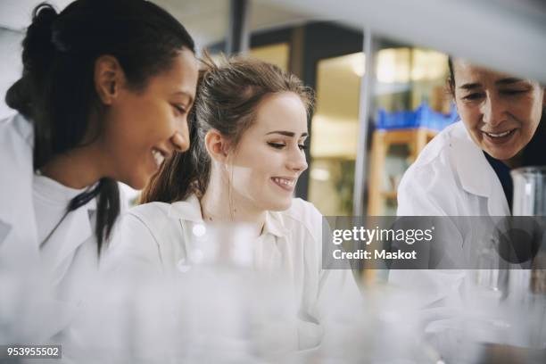 happy mature teacher with young multi-ethnic female students learning at chemistry laboratory - women in stem foto e immagini stock