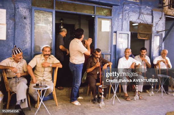 Palestiniens fumant le narguilé à la terrasse d'un café à Beyrouth en aout 1984, Liban.