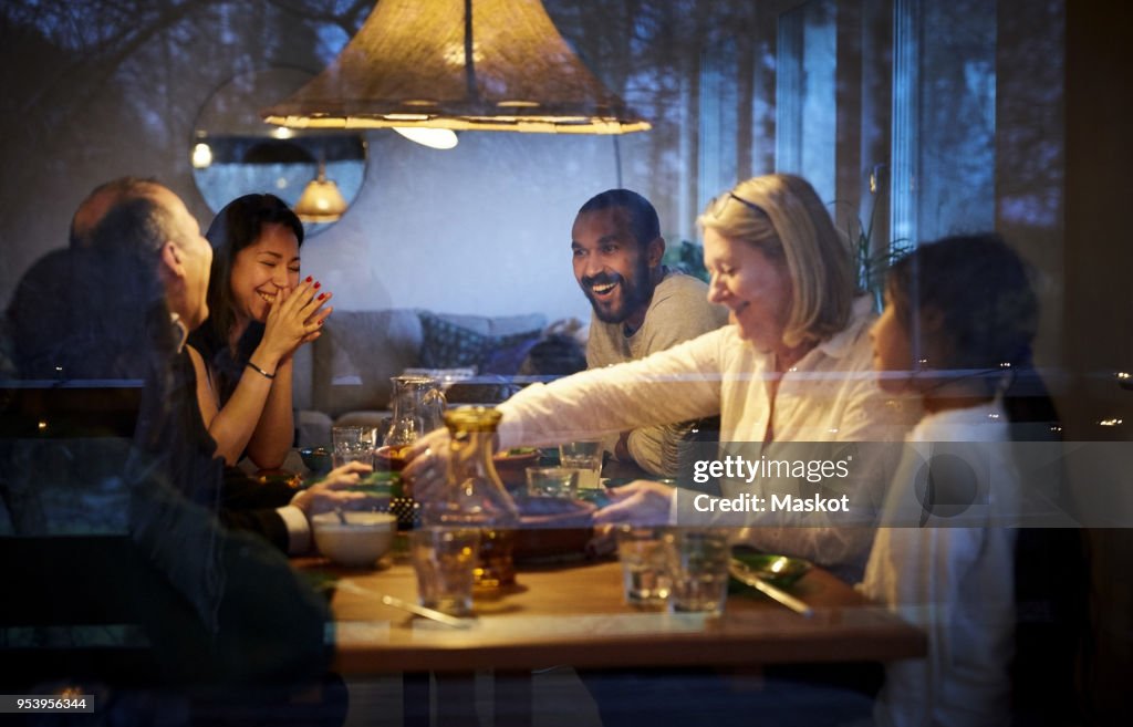 Happy family enjoying while having dinner at table seen through glass window