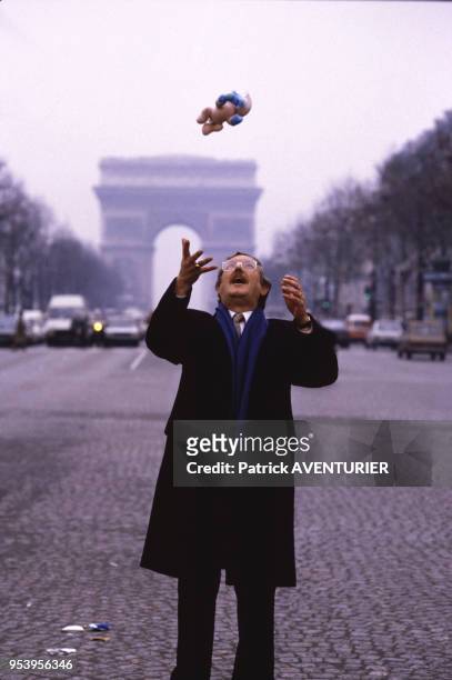 Le dessinateur belge Peyo lance en l'air la figurine d'un Schtroumpf sur les Champs-Elysées à Paris le 12 décembre 1984, France.