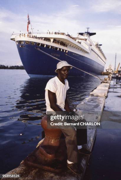 Réfugié de Cuba avec à l'arrière-plan un bateau de croisière en 1980 à Miami, Etats-Unis.