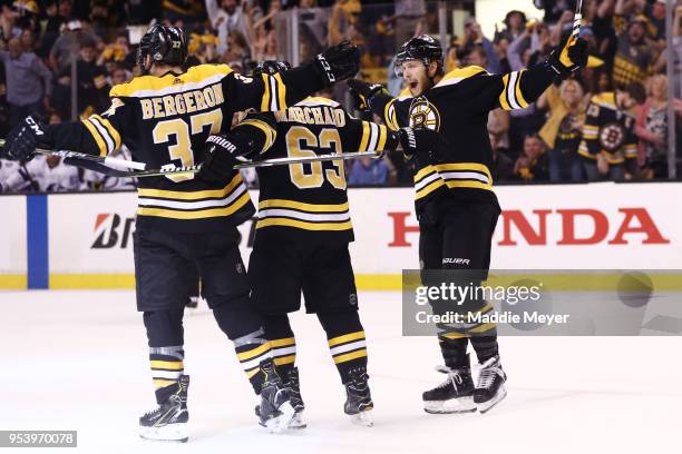 Patrice Bergeron of the Boston Bruins celebrates with Brad Marchand and David Pastrnak after scoring a goal against the Tampa Bay Lightning during...