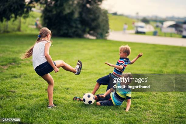 children playing football on grass in city park - young girl soccer stock pictures, royalty-free photos & images