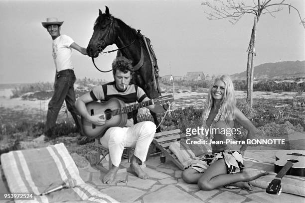 Brigitte Bardot et Johnny Hallyday jouant de la guitare sur une plage en août 1967 à Saint-Tropez, France.