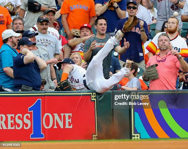 Alex Bregman of the Houston Astros dives into the stands attempting to catch a foul ball off the bat of Didi Gregorius of the New York Yankees at...