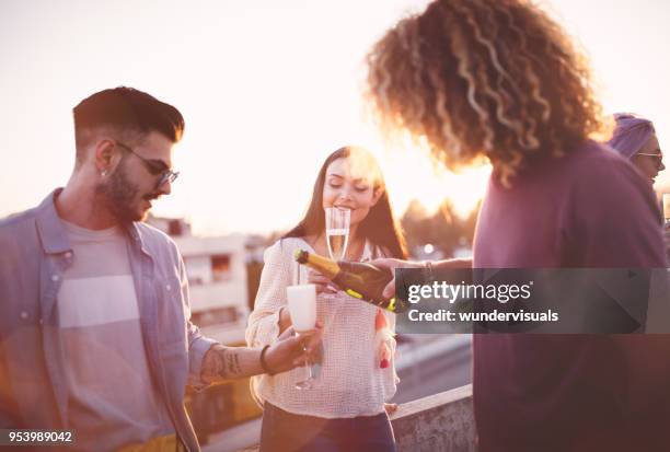 hipster friends celebrating with champagne at rooftop summer party - champagne rooftop stock pictures, royalty-free photos & images