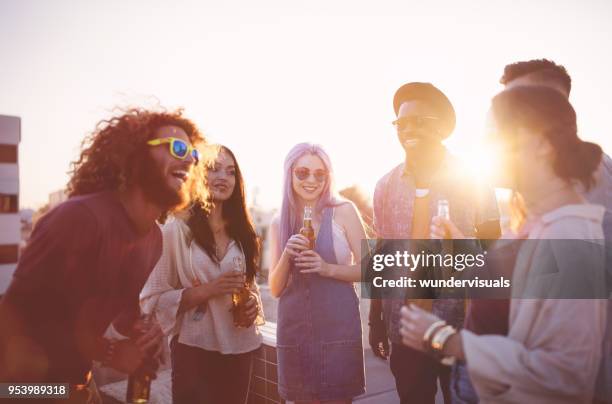hipster friends having fun and drinking beer at rooftop party - beer drinking stock pictures, royalty-free photos & images