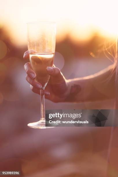 jonge vrouw hand met tatoeages champagne glazen houden bij zonsondergang - goldbarren stockfoto's en -beelden