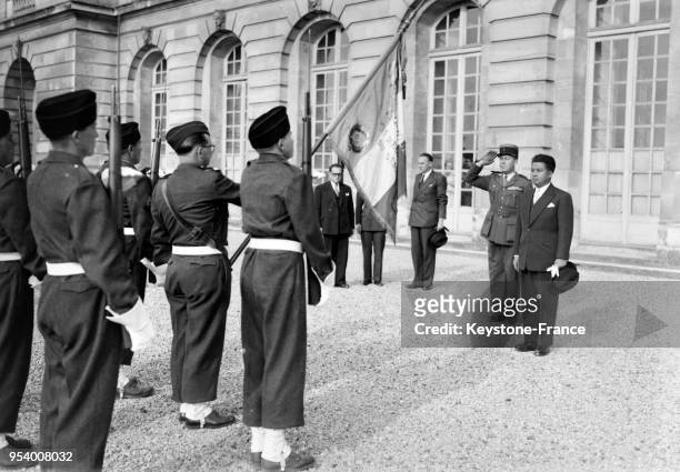 Le prince Norodom Sihanouk salue le drapeau tricolore dans la cour de l'Elysée, à Paris, France en 1946.