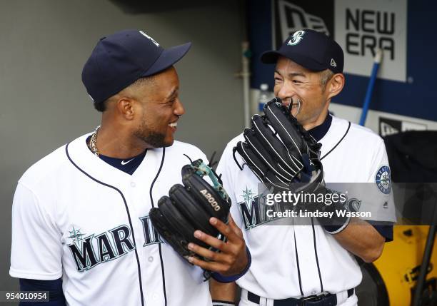 Robinson Cano of the Seattle Mariners and Ichiro Suzuki share a laugh in the dugout before the game against the Oakland Athletics at Safeco Field on...