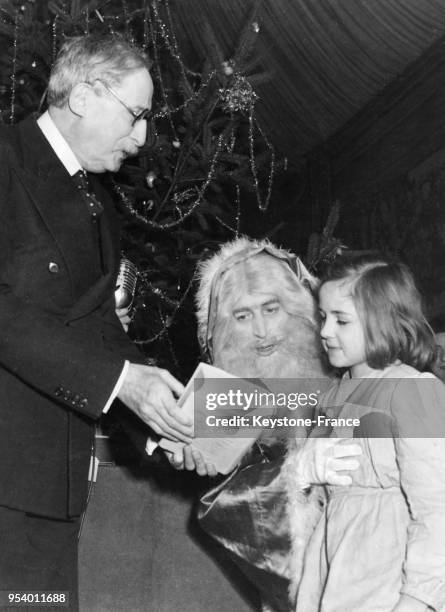 Léon Blum assisté du Père Noël distribue des jouets devant l'arbre de Noël à la présidence, à Paris, France en décembre 1946.