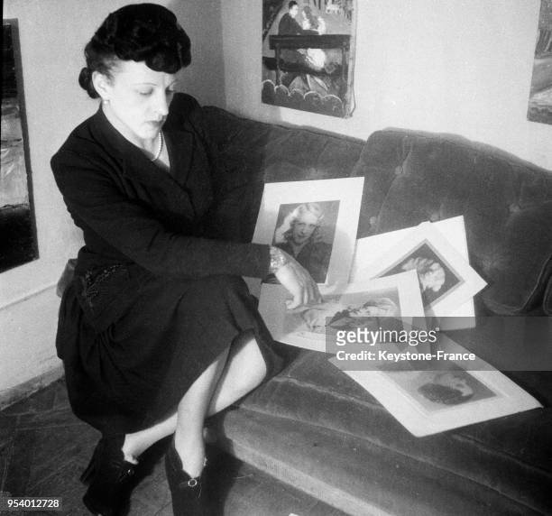 Michel-Marie Poulain, homme-femme peintre, regarde différents portraits qu'il a fait dans son atelier à Paris, France en 1946.