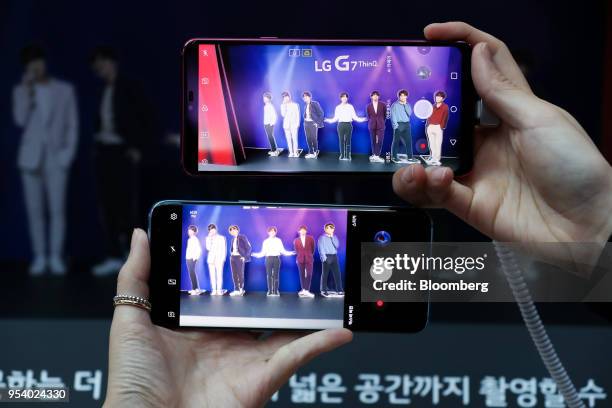 Attendees use a camera function on an LG Electronics Inc. G7 ThinQ smartphone, top, and a Samsung Electronics Co. Galaxy S8 smartphone during a...