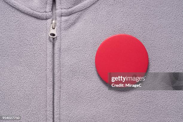 red button badge on gray cloth - spilla foto e immagini stock