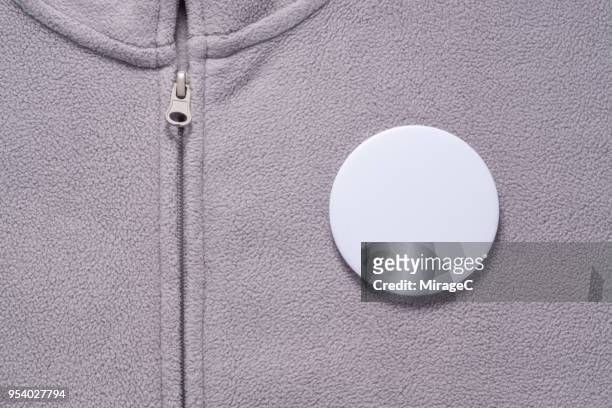 white button badge on gray cloth - brooch stock-fotos und bilder